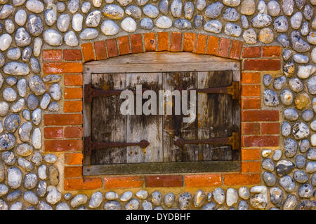 Shuttered window in brick and flint wall. Stock Photo