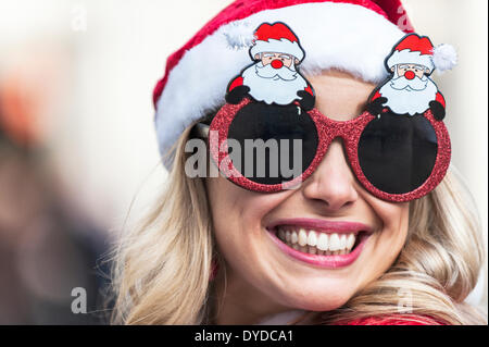 An attractive woman wearing novelty Christmas glasses attending the annual Santacon. Stock Photo