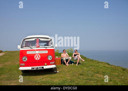 A young couple camping in a VW campervan on the clifftops over Mundesley on the Norfolk coast. Stock Photo