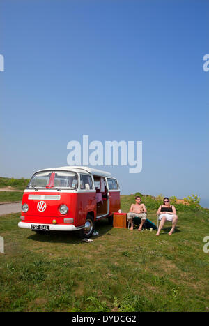 A young couple camping in a VW campervan on the clifftops over Mundesley on the Norfolk coast. Stock Photo