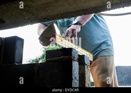 A bricklayer using a level during the building of a wall. Stock Photo