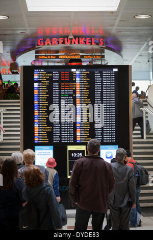Passengers checking a departure board at Gatwick Airport. Stock Photo