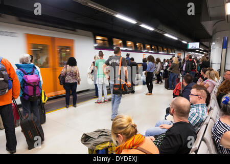 Passengers waiting on railway platform to board arriving train. Stock Photo