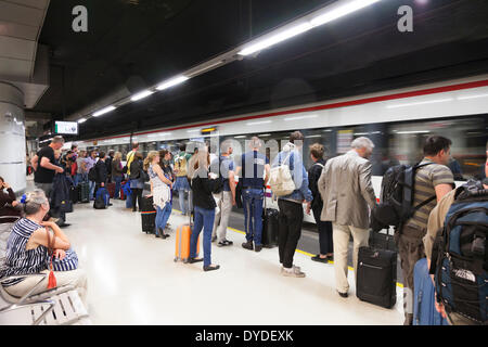 Passengers waiting on railway platform to board arriving train. Stock Photo