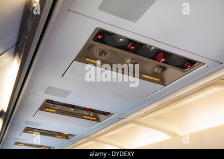 Airplane illuminated overhead No Smoking and Fasten Seat Belts signs. Stock Photo