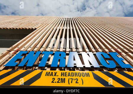 Looking up at entrance sign and wood cladding to exterior of four storey multi-storey car park. Stock Photo