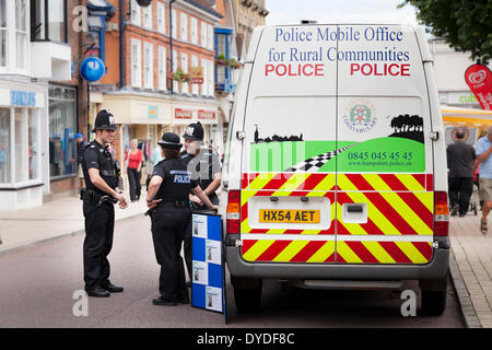 Policemen and women by police rural communities mobile office van in town high street. Stock Photo