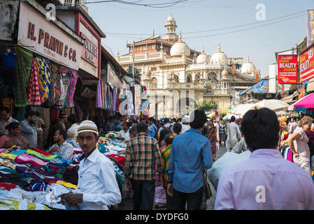 A young Muslim man in a street market with stalls selling clothes outside a large mosque. Stock Photo