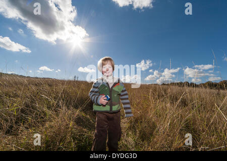 A two year old boy running in the countryside on a sunny day.