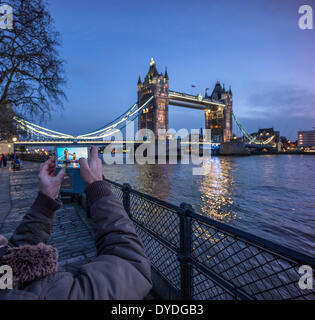 A male tourist takes a picture of Tower Bridge at night from the north side. Stock Photo