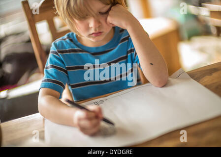 Seven year old boy drawing at the table.