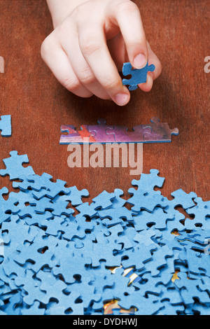 choosing of jigsaw puzzles on wooden table Stock Photo