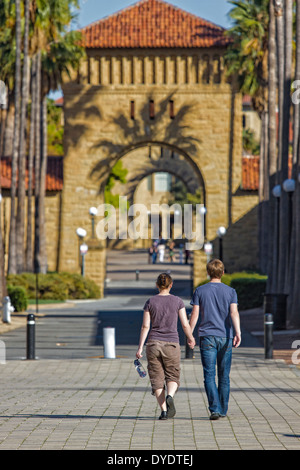 Man and woman students holding hands and walking toward arches leading to Quad on Stanford University campus Stock Photo
