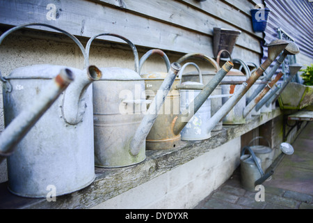 Old watering cans in a row at a local garden centre. Stock Photo