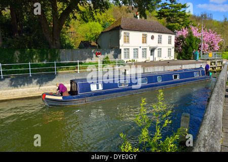 Blue Narrow boat exiting Marsh Lock on the River Thames, Henley-on-Thames, Oxfordshire, England showing the lock keepers house in spring. Stock Photo