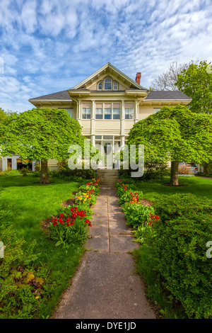 Beautiful heritage home with flowering tulips in a spring garden. Stock Photo