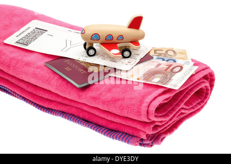 Holiday and travel concept image of a small aircraft placed onto a passport with money, an airline boarding card and towel. Stock Photo