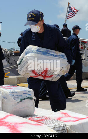 A US Coast Guard crew member offloads a bale of cocaine at from the Cutter Legare April 15, 2014 at Coast Guard Base Miami Beach, Florida. The crew of the Legare offloaded a total of $110 million of cocaine that was seized during interdiction operations in the Caribbean Sea. Stock Photo