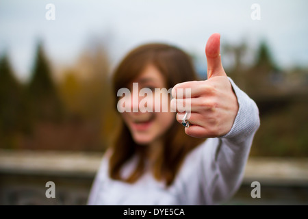 Beautiful girl doing a thumbs up sign with her hand and fingers for this unique approval image. Stock Photo