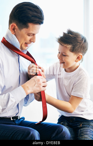 Photo of happy boy looking at his father tying necktie Stock Photo