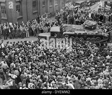 Crowds of people and a guard of honour of tanks, meeting M. Maisky, Soviet ambassador, and members of the Russian military mission when they arrived at a tank factory somewhere in Great Britain(?), where the week's tank production is for Russia, showing the 'Stalin' tank, which had just been christened by Madame Maisky 1942 or 1943. Stock Photo