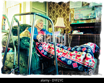 Old aged lady sitting in her chair with her cat on her lap and audio phones in her ears Stock Photo