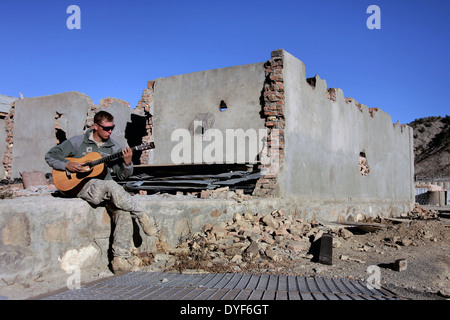 US Army Sgt. Michael Simmons plays his acoustic guitar during some down time on Combat Outpost Munoz November 12, 2009 in Afghanistan. Stock Photo