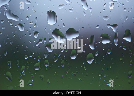 Close-up of raindrops on a window pane after heavy rain with background thrown out of focus. Stock Photo