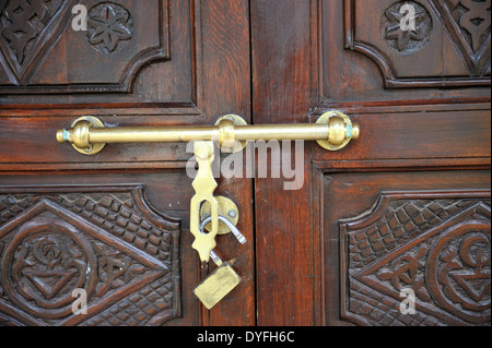 Unlocked but closed sliding bolt lock on carved wooden door Stock Photo