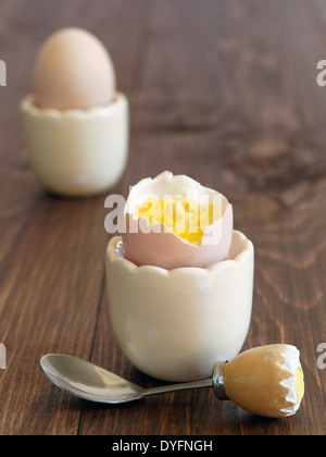 Boiled eggs in cups with a funny egg spoon Stock Photo