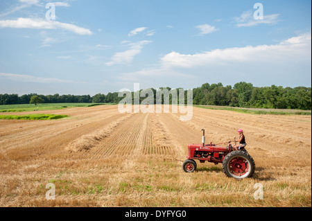 Woman farmer driving old tractor in field Stock Photo