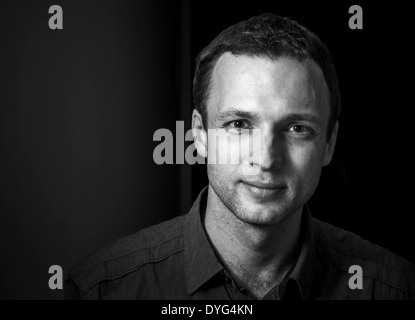 Monochrome portrait of young smiling Caucasian man on black background Stock Photo