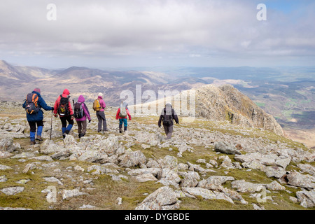 Walkers walking over rocks on Carnedd Moel Siabod north ridge in mountains of Snowdonia National Park Wales UK Britain Stock Photo