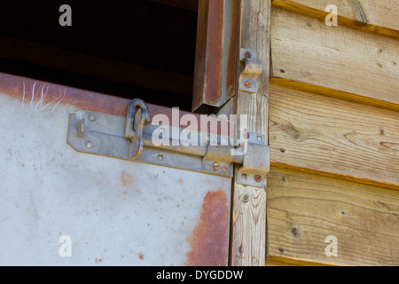 Metal sliding bolt on a metal stable door with wooden slated surround. Stock Photo