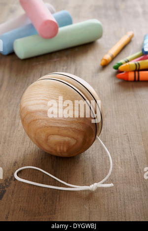 An old fashioned style wooden yoyo with chalks and wax crayons a retro childhood concept Stock Photo