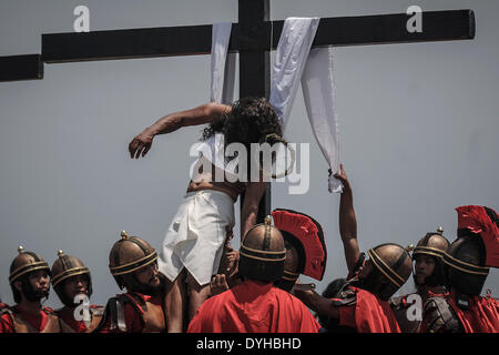 San Fernando, Philippines. 18th Apr, 2014. Penitent Ruben Enaje is brought down after taking part in a crucifixion during Good Friday in San Fernando town, Pampanga province, Philippines, April 18, 2014. Crucifixions remain a common practice during Holy Week throughout the country despite being strongly condemned by the Roman Catholic church. Penitents who take part believe the act will atone them for their sins and give them blessings.Photo: Ezra Acayan/NurPhoto Credit:  Ezra Acayan/NurPhoto/ZUMAPRESS.com/Alamy Live News Stock Photo