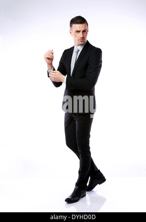 Full-length portrait of a businessman buttoning cuff sleeves on gray background Stock Photo