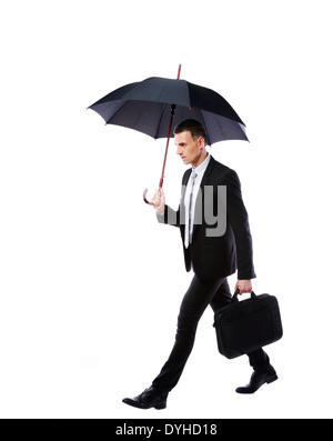 Businessman walking with umbrella and laptop bag on gray background Stock Photo