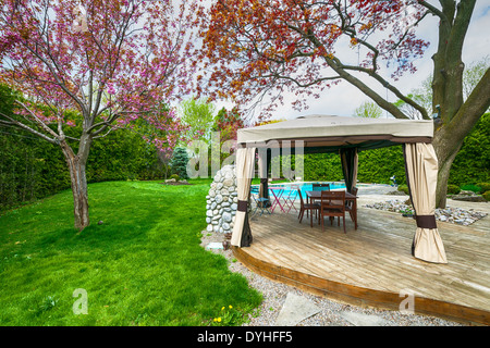 Backyard of residential house in spring with wooden deck and gazebo Stock Photo