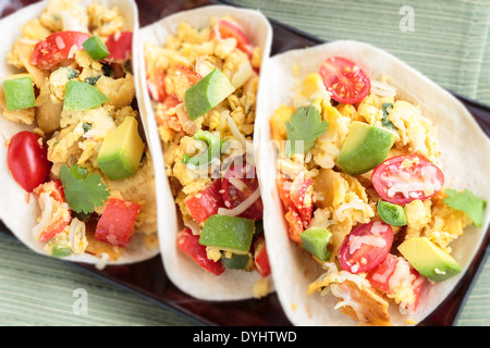 Tacos filled with migas, a Tex-Mex dish of eggs scrambled with red bell pepper, onions, jalapenos, cheese, topped with avocado Stock Photo