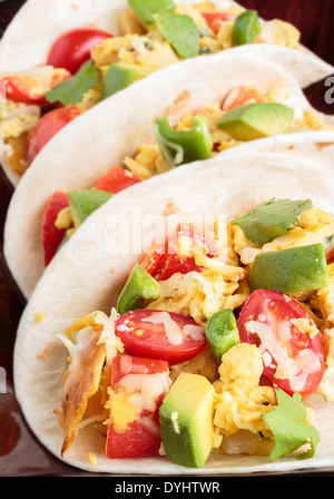 Tacos filled with migas, a Tex-Mex dish of eggs scrambled with red bell pepper, onions, jalapenos, cheese, topped with avocado Stock Photo