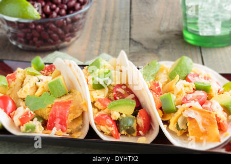 Tacos filled with migas, a Tex-Mex dish of eggs scrambled with red bell pepper, onions, jalapenos, cheese, topped with avocado Stock Photo