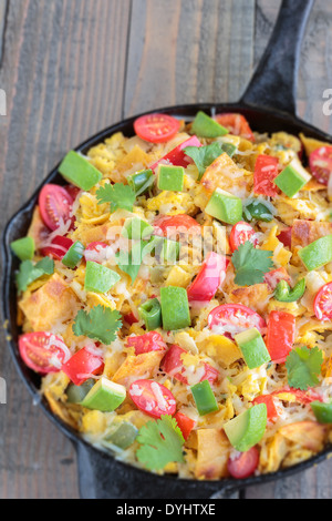 Tex-Mex breakfast migas made of eggs scrambled with onions, red bell pepper, jalapeno, cheese, with cherry tomatoes and avacados Stock Photo