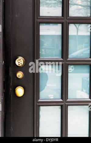 Black Lacquered Front Door Fram with Glass Panes and Reflections, Closed, showing Door Know and Two Locks Stock Photo