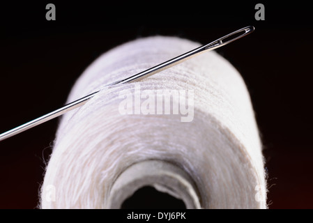 A roll of black thread and a needle on a piece of blue jeans denim Stock  Photo - Alamy