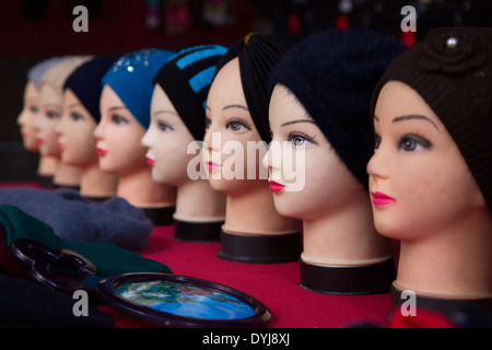 A row if mannequin heads wearing beanies in front of a mirror Stock Photo