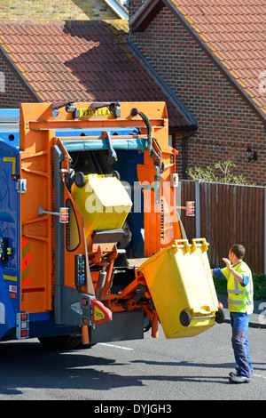 Dustman working at back of council dustcart emptying wheelie bins on hydraulic lift into lorry Stock Photo
