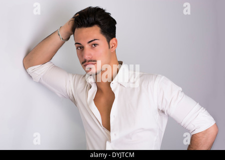 Elegant attractive young man with white shirt, leaning against wall Stock Photo