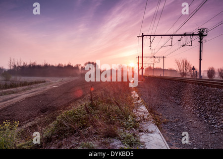 on an early morning at sunrise right next to a passing train with fog banks in the distance Stock Photo
