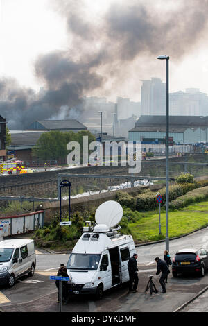 Leeds, West Yorkshire, UK, 21 April 2014. Armley Road. A pall of smoke hangs in the air as fire fighters tackle a large fire in a Leeds industrial estate. Behind are the high rise residential developments in and around the city centre. The blaze broke out at about 1.50 a.m. at the premises of Tradpak a chemical packing and recycling plant in the Armley area of the city. The factory is close to the city centre and nearby residents have been told to keep their windows and doors closed because of potentially toxic chemicals involved. Credit:  Ian Wray/Alamy Live News Stock Photo